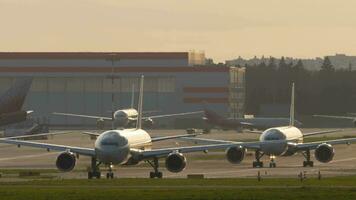 Avions sur le taxiway un après un autre dans rétro-éclairage. aérodrome, queue de jet Avions, aviation. Voyage concept video