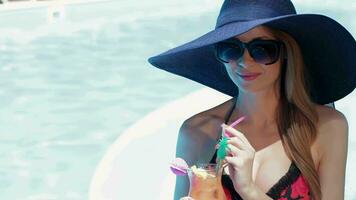 Woman holds a glass of cocktail in her hands near the swimming pool video