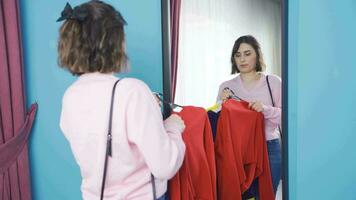 jovem mulher tentando em roupas dentro frente do espelho. video