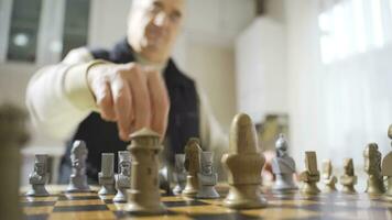 Happy retired man plays chess alone at home. video