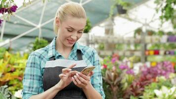 kvinna blomsterhandlare användningar henne smartphone på de trädgård Centrum video