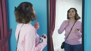 Young woman spraying perfume in front of the mirror. video