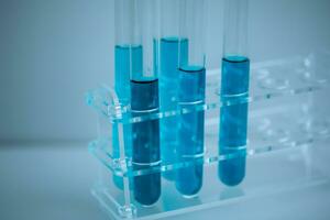 5 5 azul prueba tubos metido en un médico tubo estante con un blanco fondo, cerca arriba, médico concepto. foto
