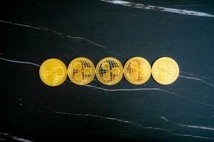 5 XRP coins lined up on a black marble background. photo