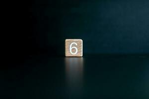 Wooden block written 6 with a Black background. photo