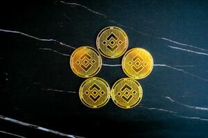 5 BNB coins BNB arranged in a circle on a black marble background. photo