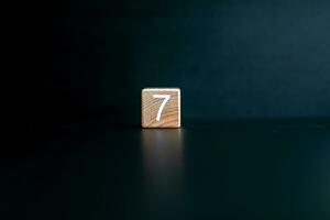 Wooden block written 7 with a Black background. photo