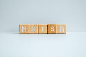 Wooden blocks form the text Harsh against a white background. photo