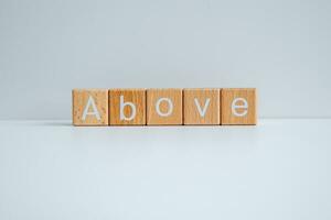 Wooden blocks form the text Above against a white background. photo