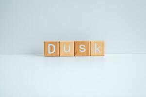 Wooden blocks form the text Dusk against a white background. photo