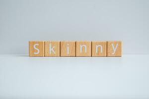 Wooden blocks form the text Skinny against a white background. photo