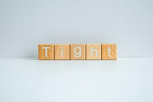 Wooden blocks form the text Tight against a white background. photo