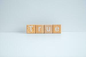 Wooden blocks form the text True against a white background. photo