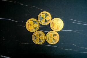 5 XRP coins XRP arranged in a circle on a black marble background. photo