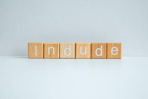 Wooden blocks form the text Indude against a white background. photo