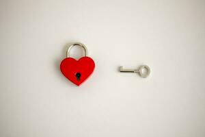 A red heart shaped padlock with one key against a white background, Love concept. photo