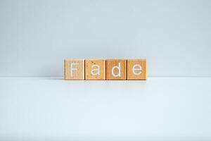 Wooden blocks form the text Fade against a white background. photo