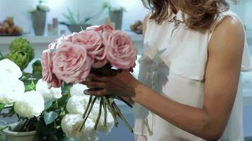 vrouw duurt een boeket van roze rozen Bij bloem winkel video