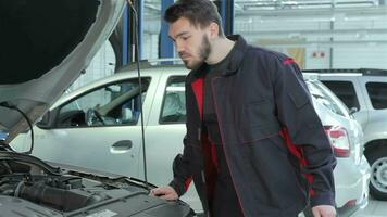 Mechaniker sieht aus unter das Auto Kapuze beim das Auto Bedienung video