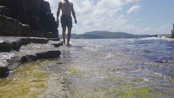 Young man walking on the seashore. video