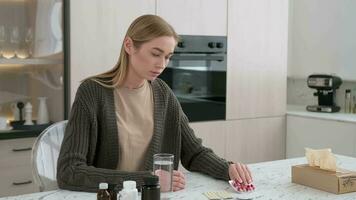 een vrouw leest de instructies voor gebruik makend van medicijnen en wast naar beneden de tablet met water. video