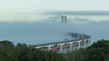 ponte 25 de abril suspensão ponte conectando Lisboa para almada dentro nuvens, névoa. Portugal. pôr do sol dia para noite Tempo lapso video