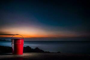 a red bucket sitting on the beach at night. AI-Generated photo