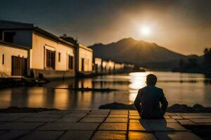 un hombre sentado en el suelo en frente de un río a puesta de sol. generado por ai foto