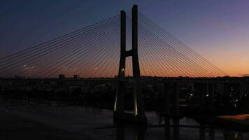 beleuchtet Vasco da Spiel Schrägseil Brücke und Lissabon Stadt beim Abend Dämmerung. Lissabon, Portugal. Blau Stunde. Antenne Sicht. Drohne fliegt nach oben, Neigung Nieder video