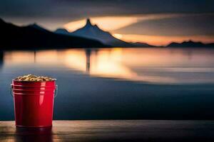 a red bucket with peanuts sitting on a table in front of a lake. AI-Generated photo