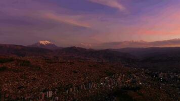 la paz paisaje urbano y Illimani montaña a noche crepúsculo. aéreo vista. Bolivia azul hora. zumbido moscas oblicuo. amplio Disparo video