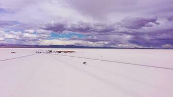 uyuni zout flats en suv auto. salar de uyuni. antenne visie. hoogvlakte, Bolivia. droog seizoen. in een baan om de aarde breed schot video