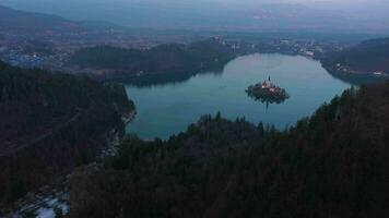 Bled Lake, Marijinega Vnebovzetja Church and Blejski Castle at Sunset. Julian Alps. Slovenia, Europe. View from Velika Osojnica Viewpoint. Aerial View. Drone Flies Forward, Tilt Up. Reveal Shot video