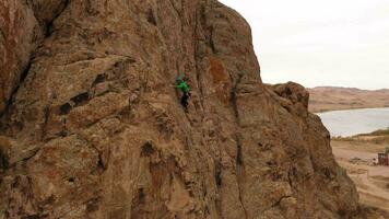 Mann Bergsteiger Felsen Klettern. Klippen im Tamgaly tas, Kasachstan. Antenne Sicht. Drohne fliegt nach oben, Neigung runter. Kran Schuss video