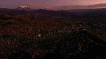 la paz paisaje urbano y Illimani montaña a noche crepúsculo. aéreo vista. Bolivia azul hora. zumbido moscas adelante, inclinación arriba. amplio disparo. revelar Disparo video