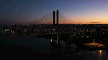 beleuchtet Vasco da Spiel Schrägseil Brücke und Lissabon Stadt beim Abend Dämmerung. Lissabon, Portugal. Blau Stunde. Antenne Sicht. Drohne fliegt nach unten, Neigung oben video