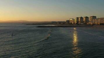 Standup Paddleboarding and Surfers in Costa Da Caparica at Sunset. Portugal. Aerial View. Orbiting video