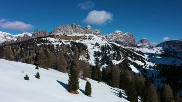 priser de cir berg räckvidd och gardena passera på solig vinter- dag. söder tyrolen, dolomiterna, Italien. antenn se . Drönare flugor framåt- över träd på låg nivå video