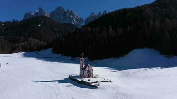 kyrka av st john, skog och dolomiter på solig vinter- dag. söder tyrolen, Italien. antenn se. Drönare flugor bakåt och uppåt video