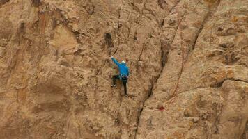 homem alpinista Rocha escalando. falésias dentro Tamgaly tas, Cazaquistão. aéreo visualizar. órbita video
