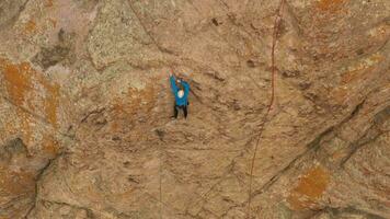 Mann Bergsteiger Felsen Klettern. Klippen im Tamgaly tas, Kasachstan. Antenne Sicht. Drohne fliegt nach unten, Neigung hoch. Kran Schuss video