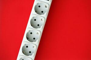 White electrical multi plug extender with european socket on bright red background photo