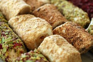 Rolls of turkish delight with many different flavors and fillings close up on table of vendors market photo