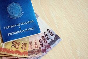 Brazilian work card and social security blue book and reais money bills photo