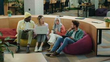 multi-etnisch bedrijf team van collega's bespreken een project terwijl zittend Aan Ottomanen in een modern kantoor.anders rassen, divers mensen, creatief team, bedrijf partners video