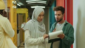 A Muslim business woman and a European businessman are discussing a project while standing in the corridor.Different Races,Diverse People,Creative Team,Business Partners video