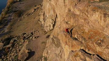 Man Climber is Belaying from an Anchor on Multi-pitch. Rock Climbing in Tamgaly Tas, Kazakhstan. Aerial View. Drone Flies Forward, Tilt Down video