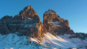 Tre Cime Di Lavaredo. The Three Peaks at Sunrise in Winter and Auronzo Hut. Aerial View. Sexten Dolomites, South Tyrol. Italy. Orbiting. View from the South video