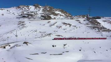 Train in Switzerland near Bernina Pass on Sunny Winter Day. Bernina Railway. Swiss Alps. Aerial View. Drone Flies Sideways video