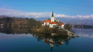 blödde sjö, marijinega vnebovzetja kyrka och blejski slott. julian alps och reflexion i de sjö. slovenien. antenn se. Drönare flugor bakåt och uppåt video